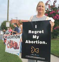 Lady holding sign," I regret my abortion" outside the mill